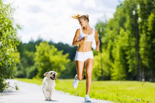 Девушка бежит в парке со своей собакой