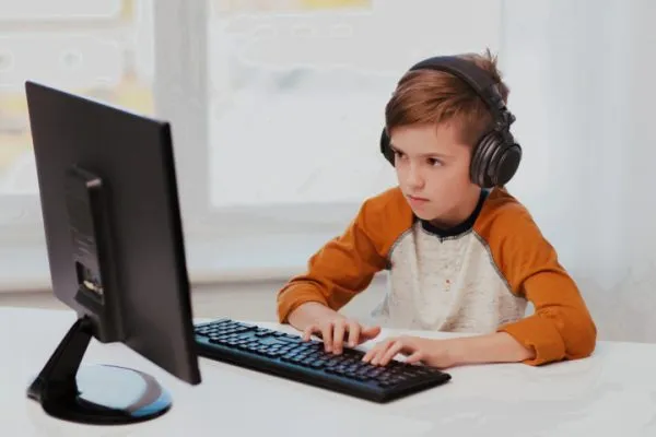 Мальчик в наушниках играет на компьютере