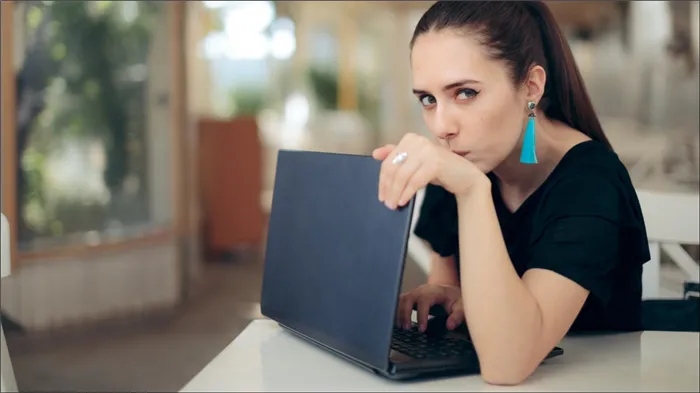 Неуверенная в себе женщина закрывает ноутбук, чтобы сохранить конфиденциальность.